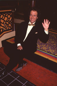 Richard Simmons sitting on steps waving in tuxedo photo print.