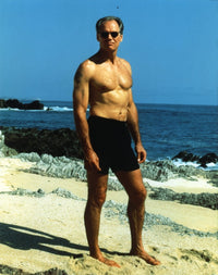 Fred Dryer standing on sand in swimming trunks photo print