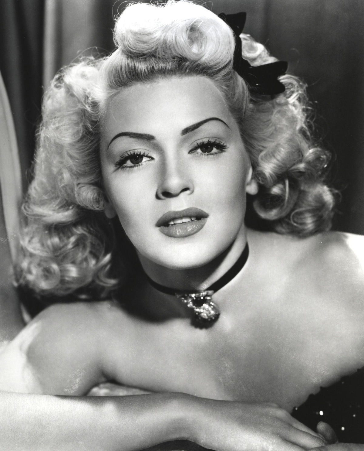 Close-up portrait of Lana Turner with ribbon and amulet necklace, vintage photo print.