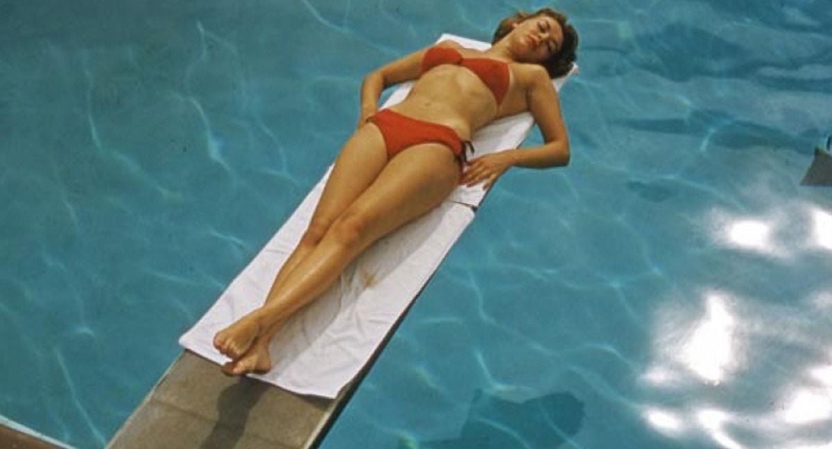 Gene Tierney laying on a diving board in an orange bikini photo print