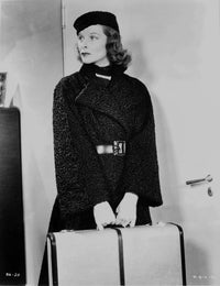 Black and white photo print of Katharine Hepburn wearing a black coat and cap