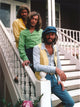 Bee Gees band group photo on white staircase in colorful shirts.
