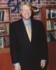 Jerry Springer smiling portrait photo print in black suit.