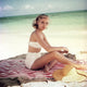 Grace Kelly lounging on a striped towel in a white bikini photo print.