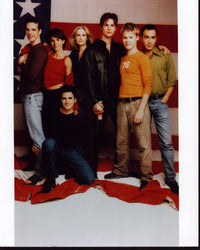 Queer As Folk cast photo print in front of American flag.