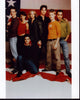 Queer As Folk cast photo print in front of American flag.