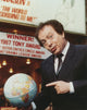 Jackie Mason photo print in suit and tie pointing at a globe.