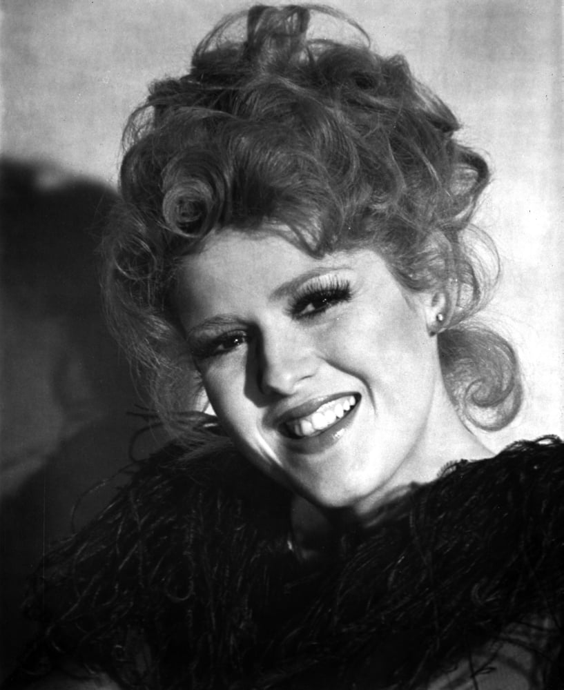Bernadette Peters smiling portrait in black dress with feather boa