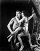 Johnny Weissmuller carrying a girl in a movie scene photo print.