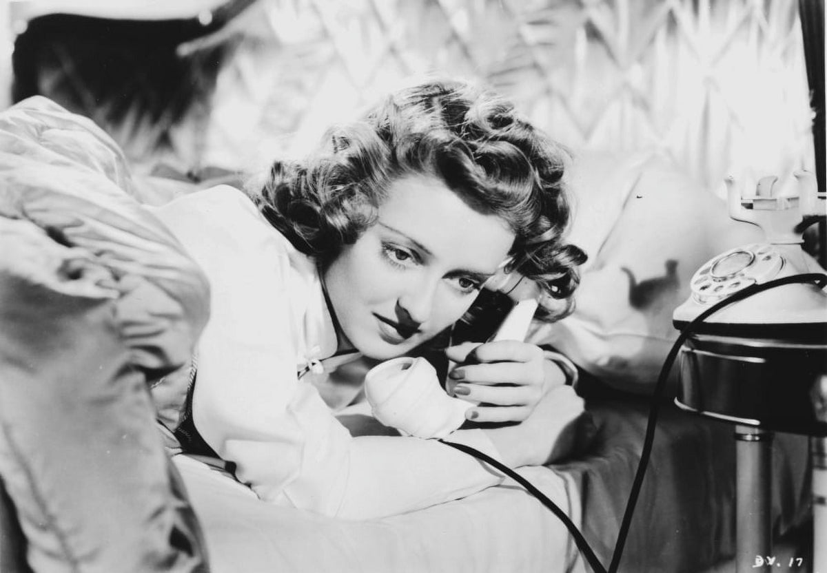 Bette Davis lying on bed talking on phone in white silk shirt photo print