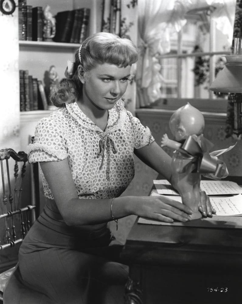 Doris Day seated in a classic candid photo with a doll, available as a print.