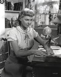 Doris Day seated in a classic candid photo with a doll, available as a print.
