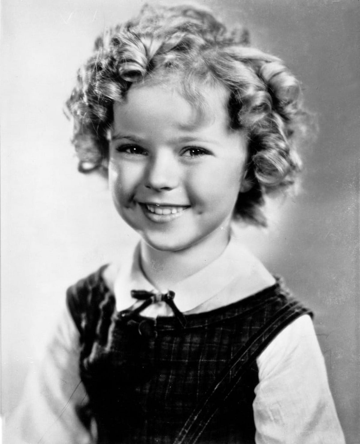 Shirley Temple photo print wearing a white blouse and black gymslip.