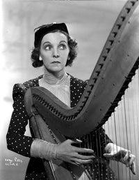 Zasu Pitts looking away while playing a harp in polka dot dress photo print.
