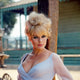 Elke Sommer leaning on a post in a white low-cut dress photo print.