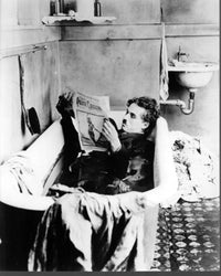 Black and white photo print of Charlie Chaplin reading a newspaper in a bathtub.