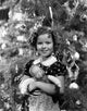 Shirley Temple holding doll in front of Christmas tree, 1930s photo print.