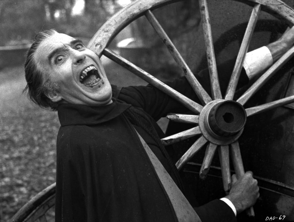 Film still of Christopher Lee as Dracula next to a wagon wheel