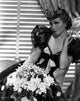 Claudette Colbert seated in a black elegant dress with flowers photo print