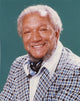 Close-up portrait photo print of Redd Foxx smiling in a coat.