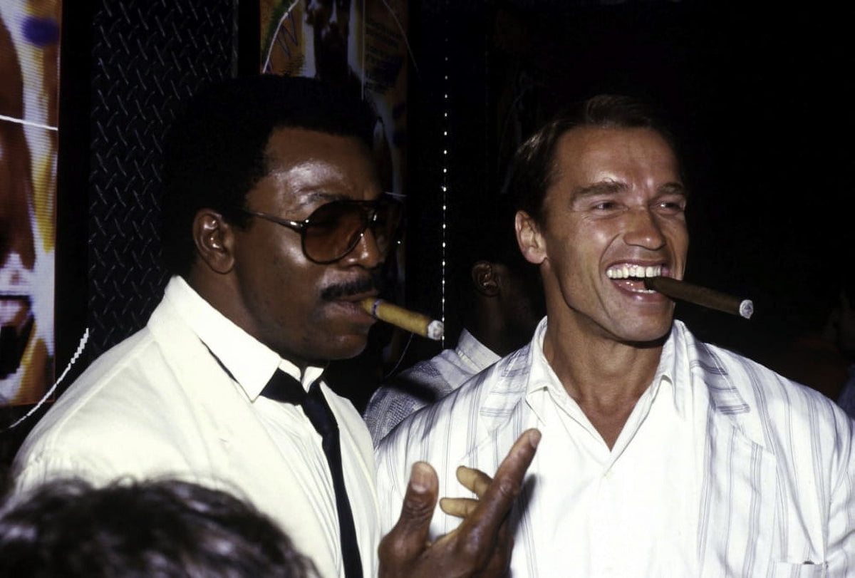 Arnold Schwarzenegger and Carl Weathers Smoking Cigars Photo Print