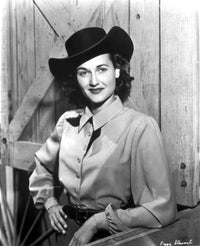 Peggy Stewart leaning on a wooden door in a cowboy outfit portrait photo print.
