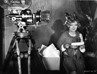 Black and white photo print of Marion Davies beside a camera.
