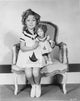 Shirley Temple sitting on a chair with doll in a white dress photo print