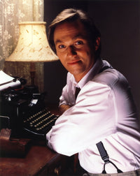 Richard Thomas smiling next to a typewriter photo print