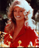Farrah Fawcett photo print in red top surrounded by flowers.