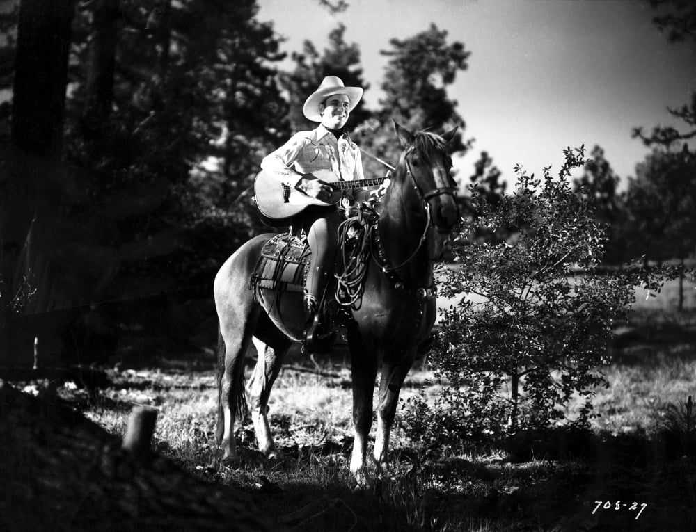 Gene Autry riding a horse while carrying a guitar photo print