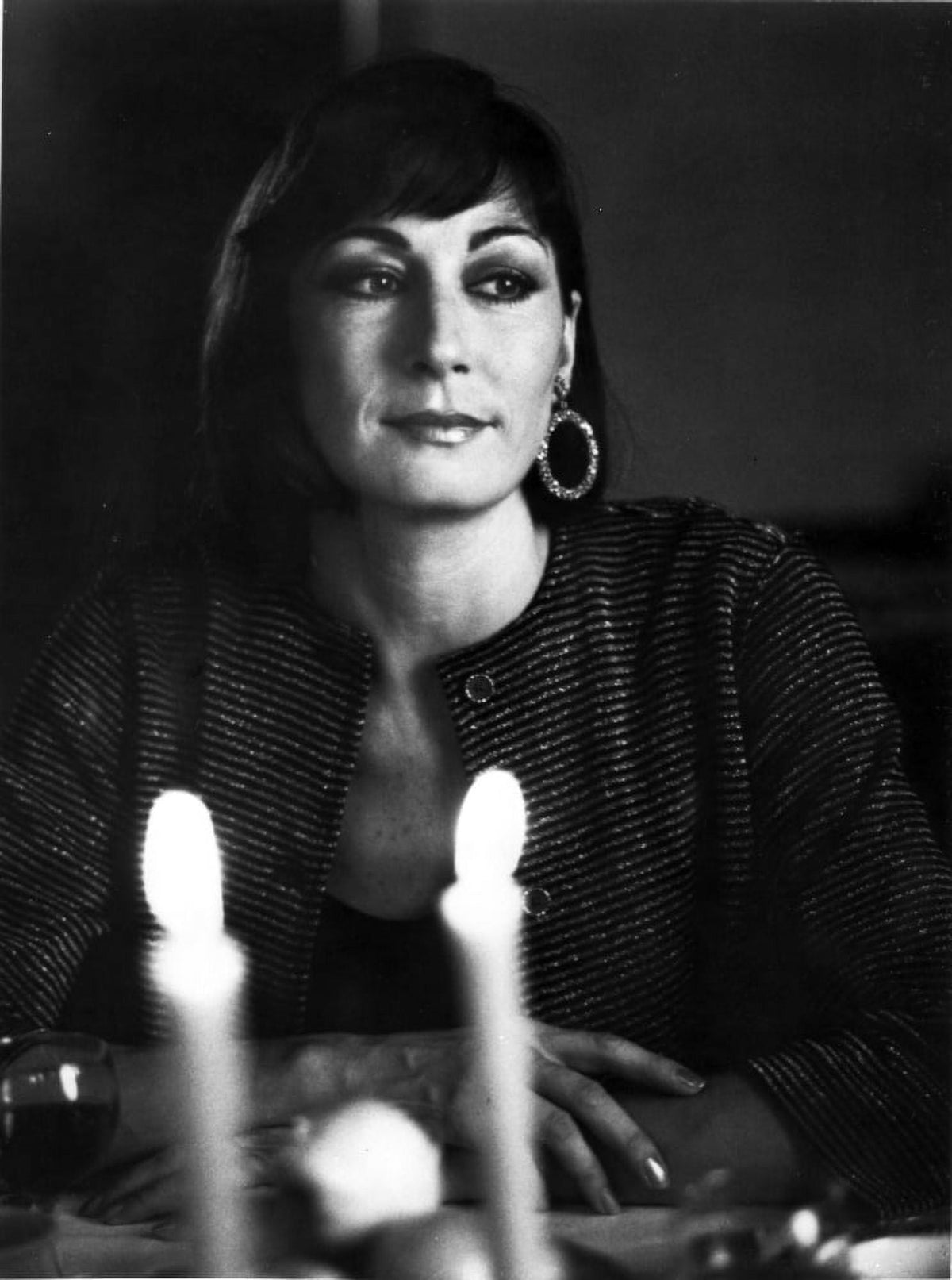 Anjelica Huston portrait photo print at a dining table wearing loop earrings.