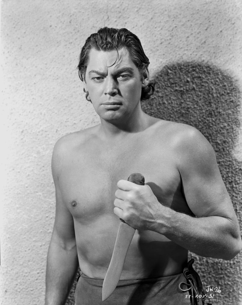 Johnny Weissmuller holding a knife in a classic movie scene photo print.