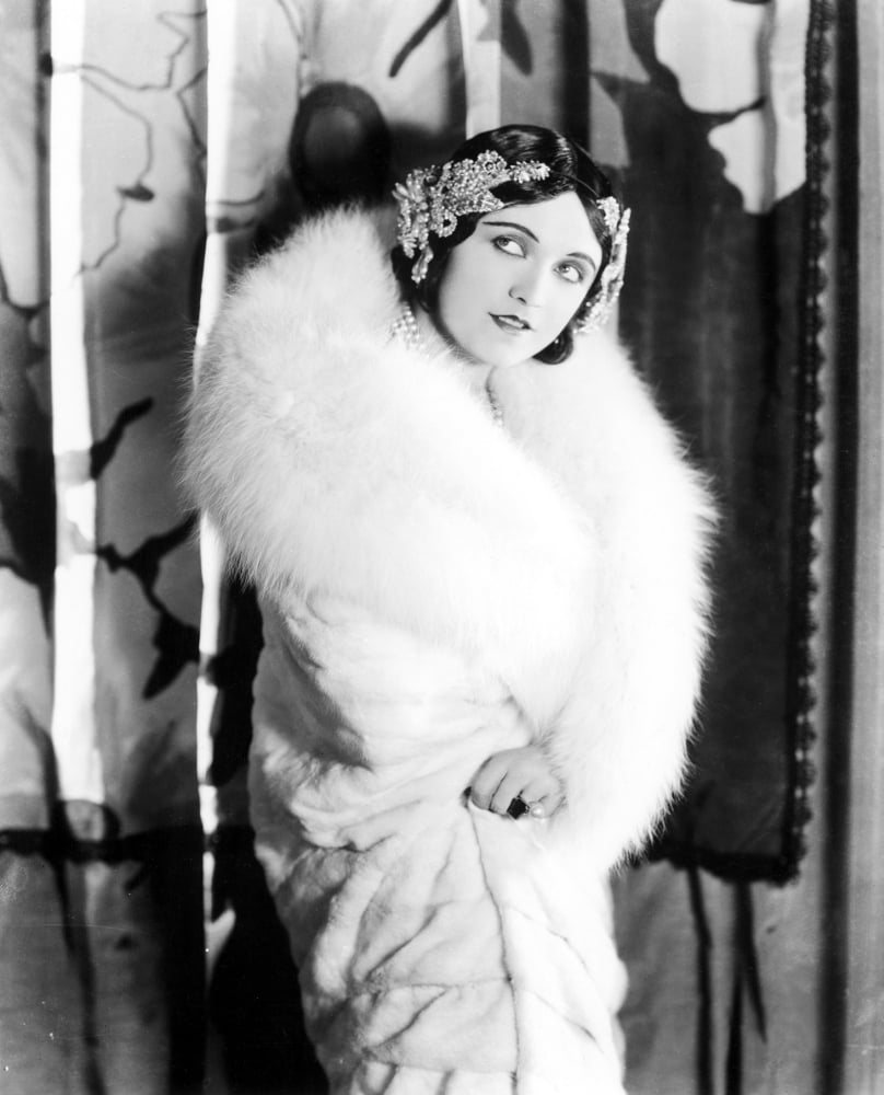 Vintage photo print of Pola Negri wearing a white knee-length fur coat from the late 1920s.