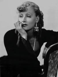 Greta Garbo photo print leaning on chair in black outfit.