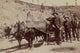 Five men with pick axes standing next to a wagon pulled by oxen.