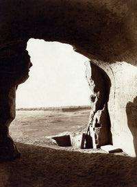 Desert view from inside a rock-cut tomb with hieroglyphics.