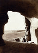 Desert view from inside a rock-cut tomb with hieroglyphics.