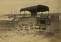 Covered wagon with side curtains rolled up at a military facility poster print