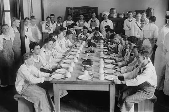 Naval Cadets at Newport sitting in disciplined formation before a meal.