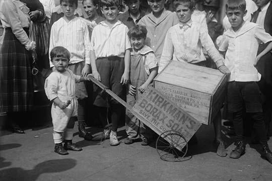 Toddler holding a Soap Box Derby vehicle surrounded by friends poster print.