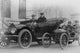 Poster print of two men in a large auto with two men in a miniature auto.