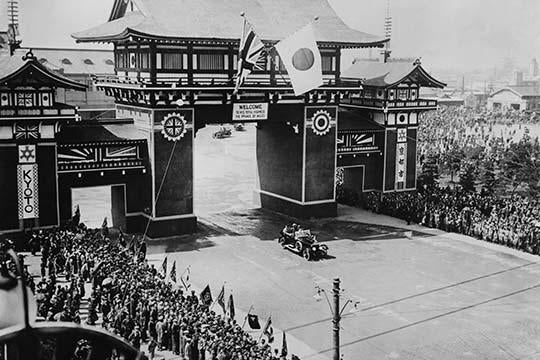 Prince of Wales Motorcade in Kyoto, Japan Poster Print with British and Japanese flags above an archway.