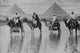 Camels with Native Riders in Floodwaters with Pyramids of Giza Poster Print