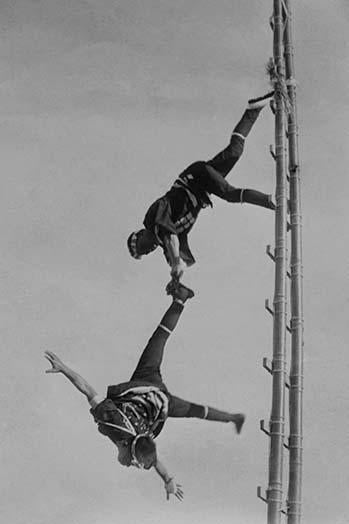 Two Tokyo Firefighters performing acrobatics on high bamboo ladders poster print.