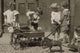 Poster print of four young children loading rocks into a wagon while a smaller child plays with a toy pony cart.