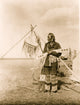 Blackfoot man full-length portrait poster print standing in a field holding decorated sheaths.