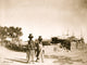 Two Pueblo women carrying jugs on their heads in a scenic desert landscape poster print.
