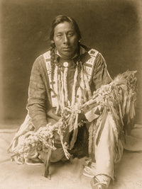 Piegan Man Full-Length Portrait Poster Print featuring a kneeling man holding a medicine pipe.