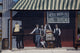 Charming bakery scene poster print featuring people and a child on a tricycle.